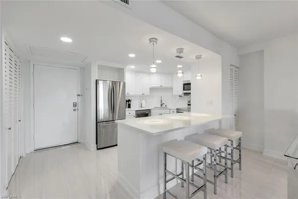 a kitchen with a sink a refrigerator and white cabinets