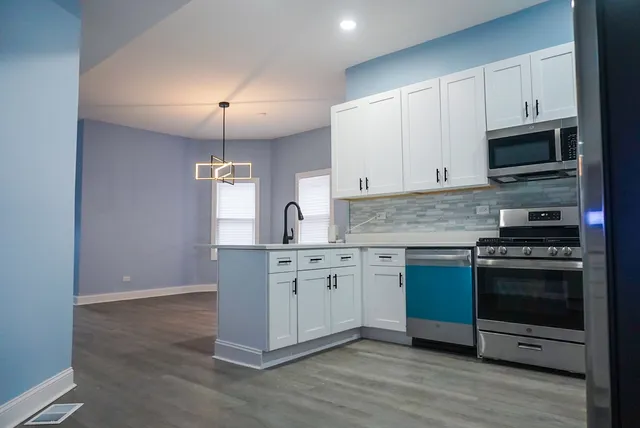 a kitchen with granite countertop white cabinets stainless steel appliances and a counter space