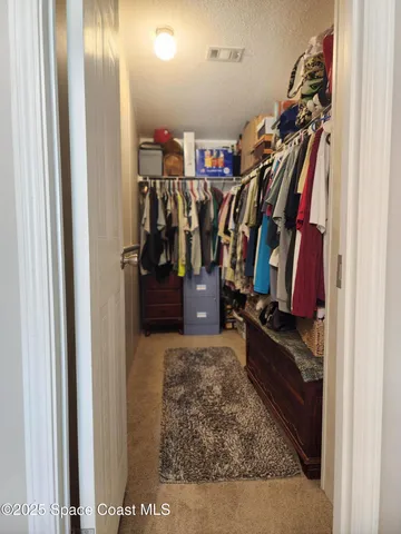 a view of walk in closet with clothes and shoes