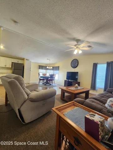 a living room with furniture a chandelier and a dining table