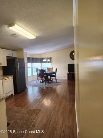 a view of a livingroom with furniture wooden floor kitchen and windows
