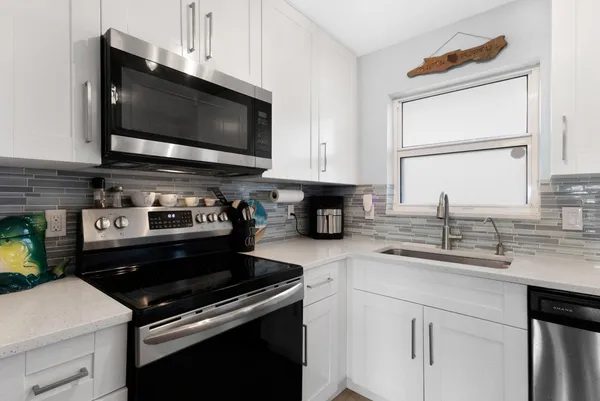 a kitchen with white cabinets and stainless steel appliances