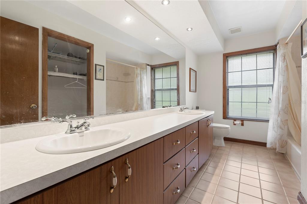 18321 McMullen Road Spring Hill, FL 34610 - Photo 32 of 56 a bathroom with a double vanity sink a mirror and a bathtub
