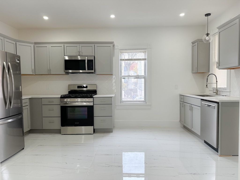 70 Nelson Street, Unit 2 Boston, MA 02124 - Photo 3 of 12 a kitchen with stainless steel appliances a refrigerator stove and microwave