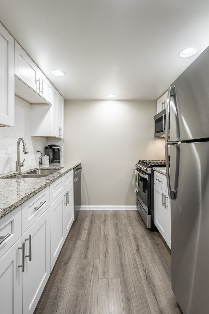 154 East Bailey Road, Unit F Naperville, IL 60565 - Photo 8 of 25 a kitchen with a sink a refrigerator and cabinets