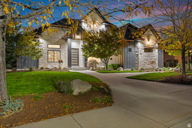 View of front facade featuring stone siding, a lawn, and board and batten siding