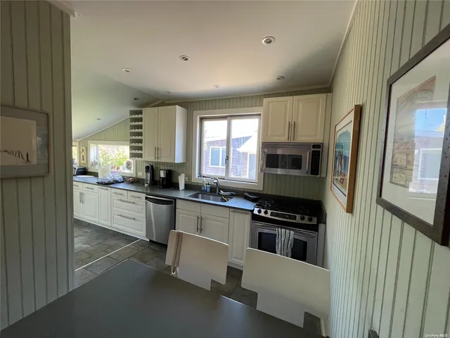 a kitchen with stainless steel appliances a refrigerator a stove a sink and white cabinets