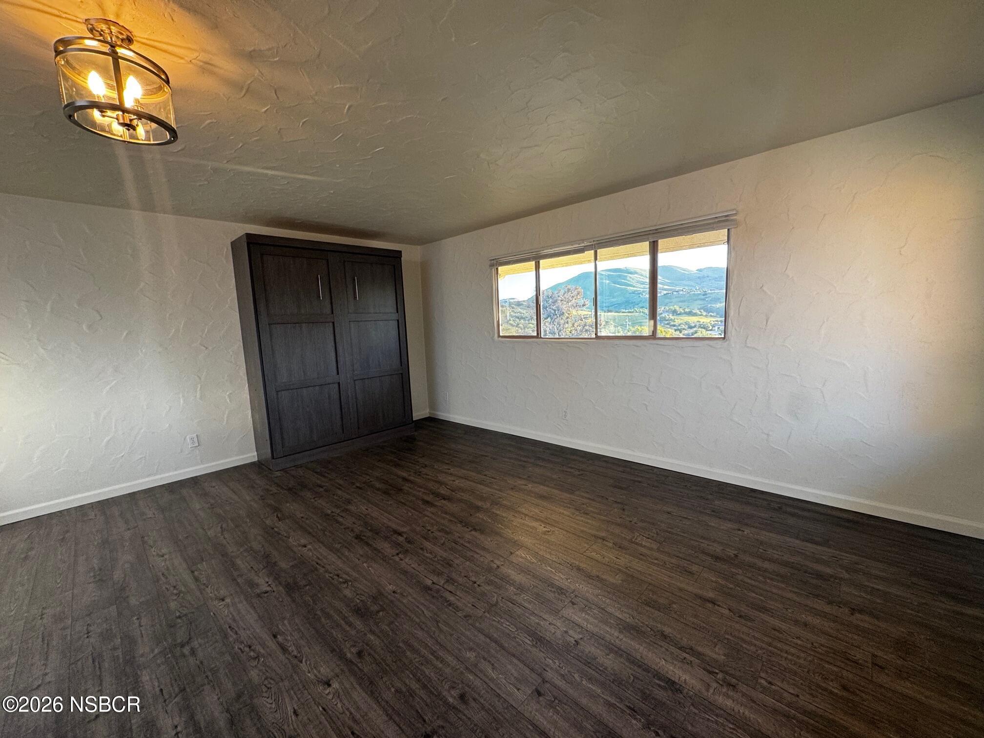 460 Rim Rock Road Nipomo, CA 93444 - Photo 3 of 7 an empty room with wooden floor and windows