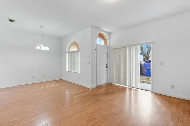 a view of an empty room with window and wooden floor