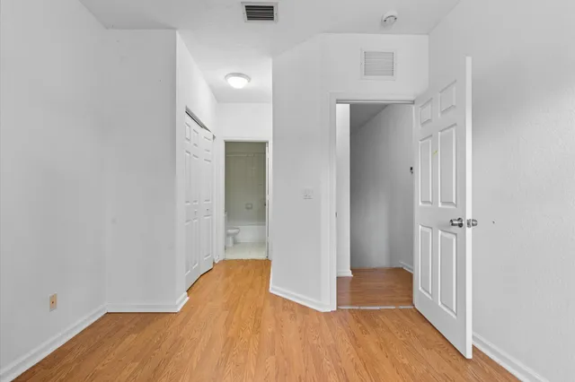 an empty room with wooden floor and entrance
