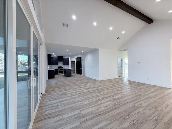 a large kitchen with stainless steel appliances kitchen island a large counter top and oven a sink with wooden floor