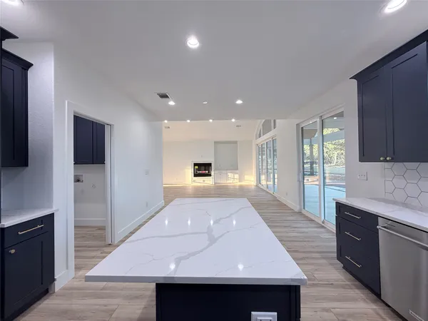 a large kitchen with stainless steel appliances kitchen island granite countertop a refrigerator and a stove top oven