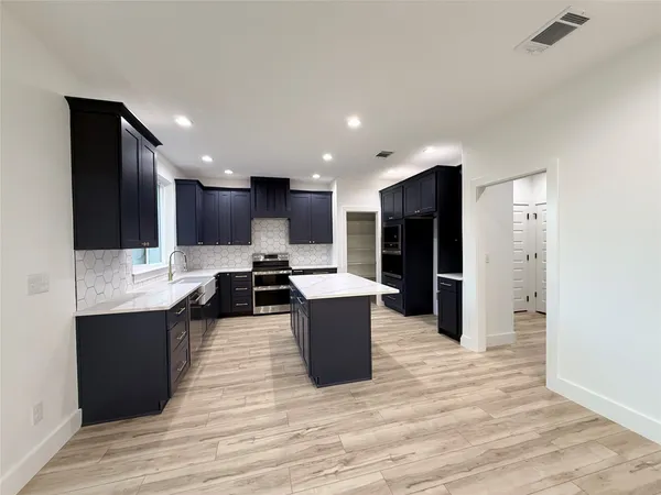 a kitchen with a sink wooden floor and stainless steel appliances