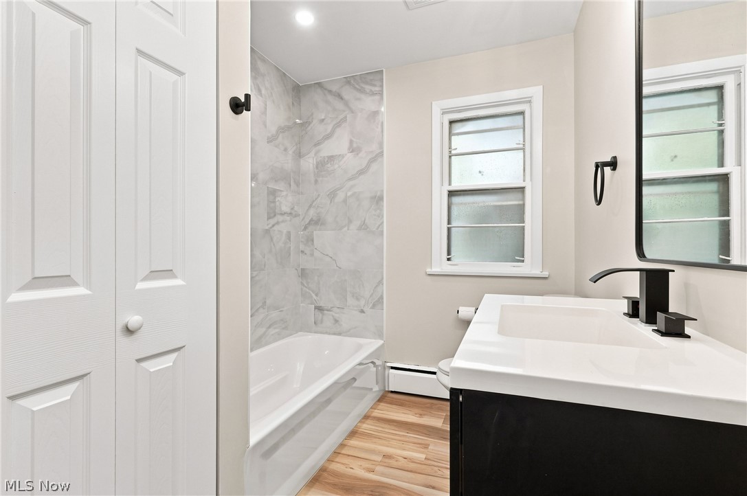 7524 Root Road North Ridgeville, OH 44039 - Photo 24 of 50 Bathroom featuring a built-in bathtub with subway tile surround, wood-finish flooring, and a vanity with an integrated sink
