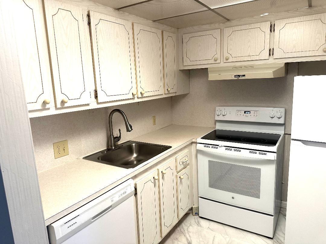 562 Fanshaw North, Unit 5620 Boca Raton, FL 33434 - Photo 6 of 15 a kitchen with granite countertop white cabinets and white appliances
