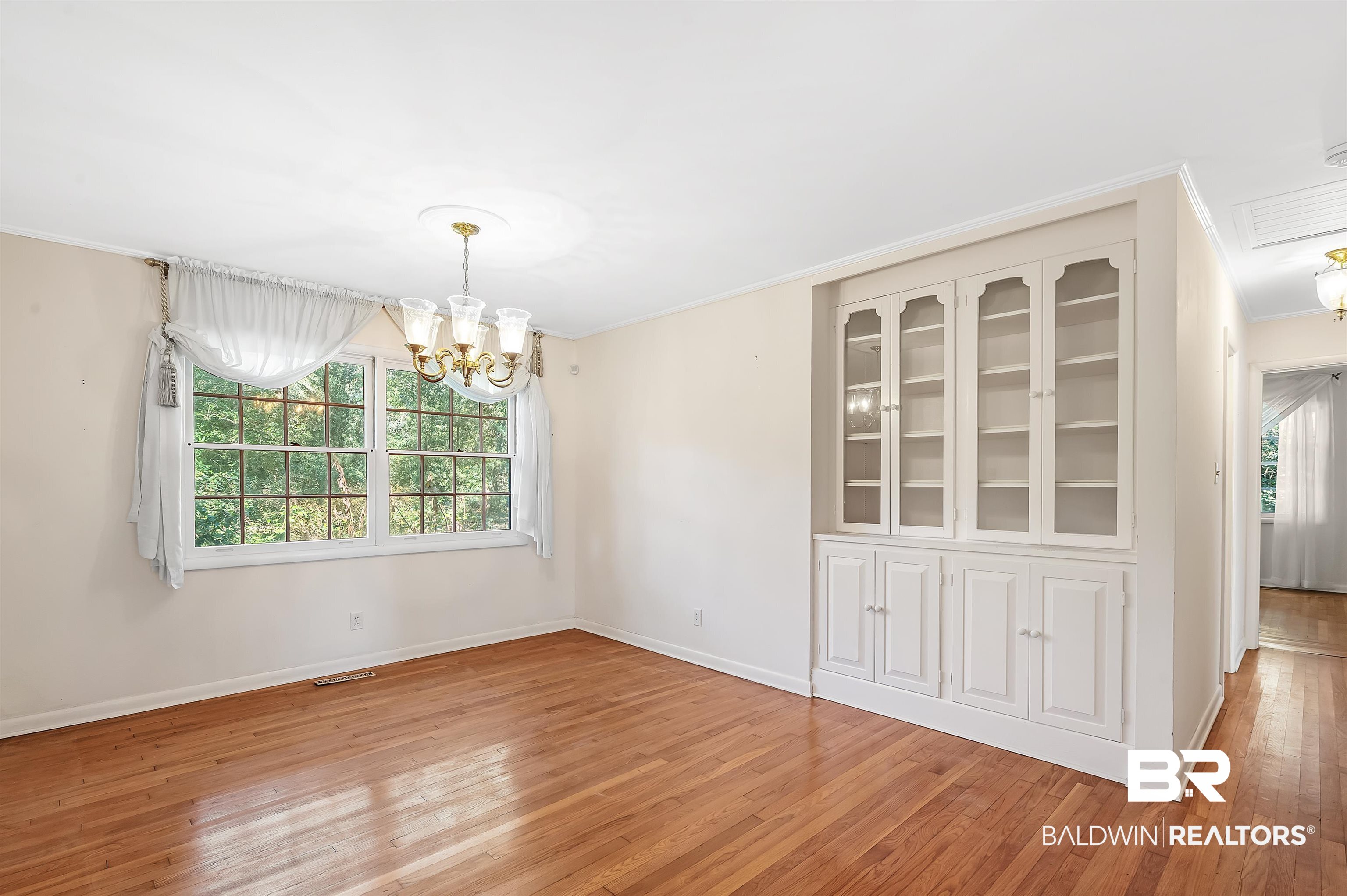14375 Oak Street Magnolia Springs, AL 36555 - Photo 9 of 20 Empty room with ornamental molding, a healthy amount of sunlight, and oak hardwood floor