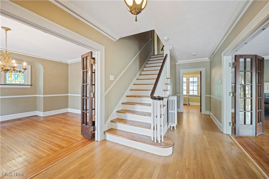 24510 Lake Road Bay Village, OH 44140 - Photo 5 of 45 Foyer entrance featuring ornamental molding, a chandelier, stairway, wood finished floors, and radiator