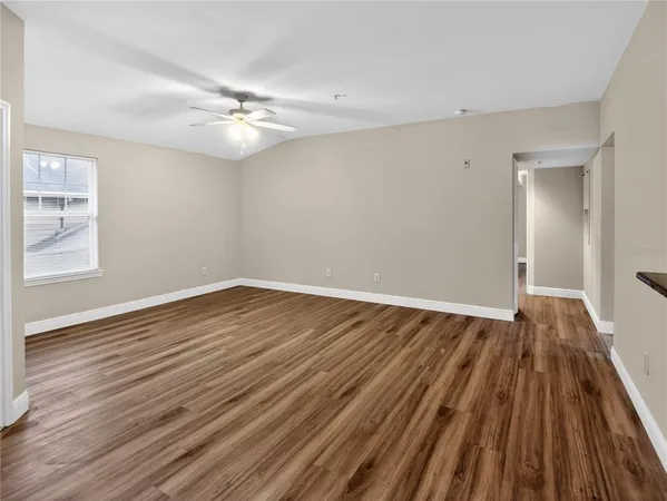 a view of an empty room with wooden floor and a window