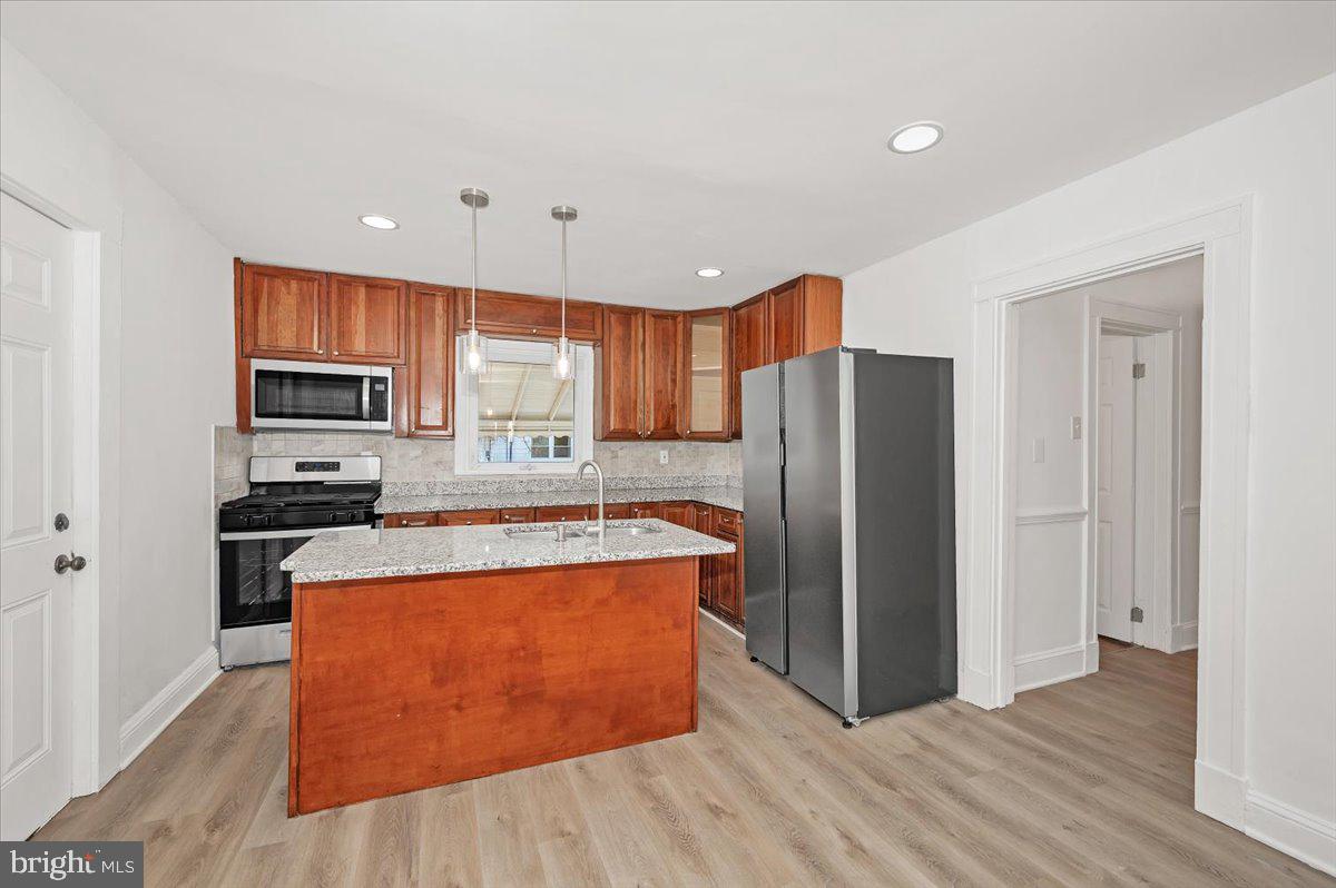 3503 Garrison Boulevard Baltimore, MD 21215 - Photo 14 of 68 a kitchen with stainless steel appliances granite countertop a refrigerator a stove top oven a sink and dishwasher with wooden floor