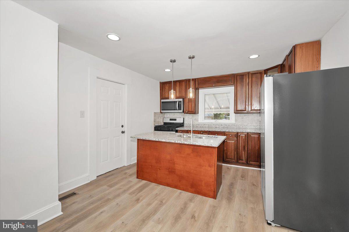 3503 Garrison Boulevard Baltimore, MD 21215 - Photo 16 of 68 a kitchen with stainless steel appliances granite countertop a refrigerator a sink dishwasher a stove with wooden cabinets and floor