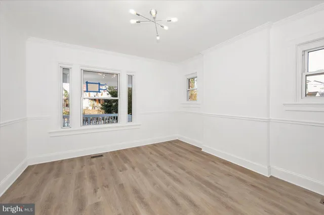 an empty room with wooden floor and ceiling fan