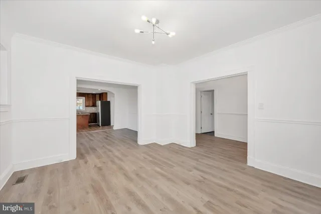 a view of kitchen and empty room with wooden floor