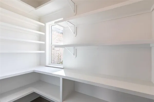 an empty room with chandelier fan and windows