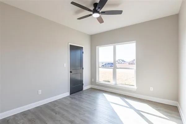 an empty room with wooden floor closet and windows