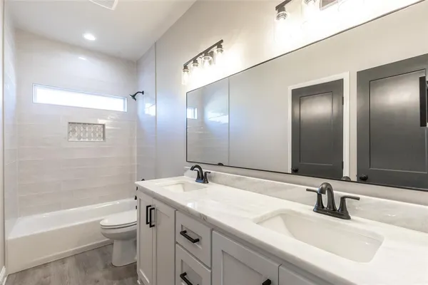 a bathroom with a double vanity sink a large mirror and a bathtub