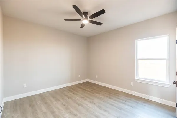 an empty room with wooden floor closet and ceiling fan