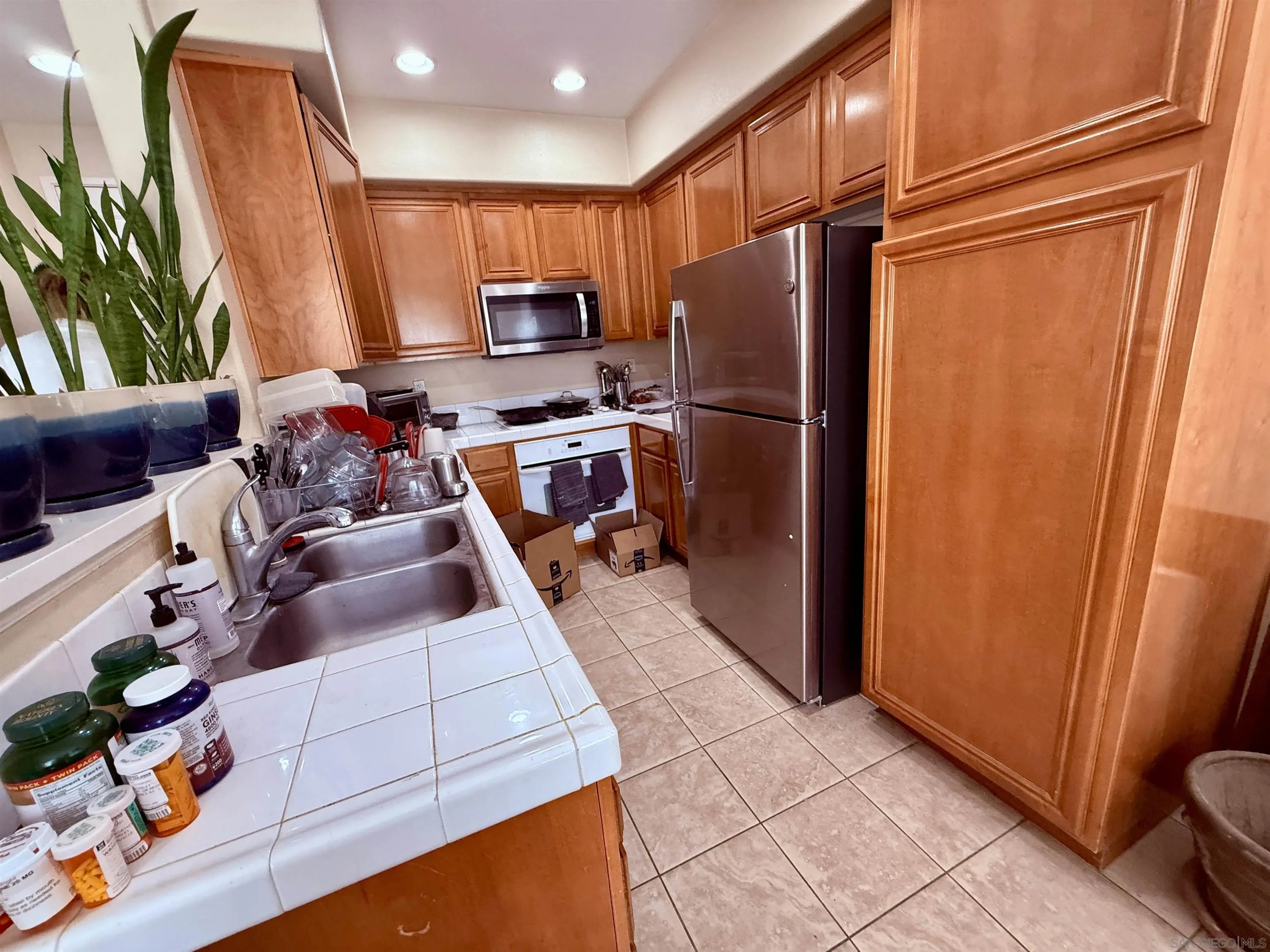 6471 Terraza Portico Carlsbad, CA 92009 - Photo 14 of 19 a kitchen with stainless steel appliances a refrigerator sink and wooden cabinets