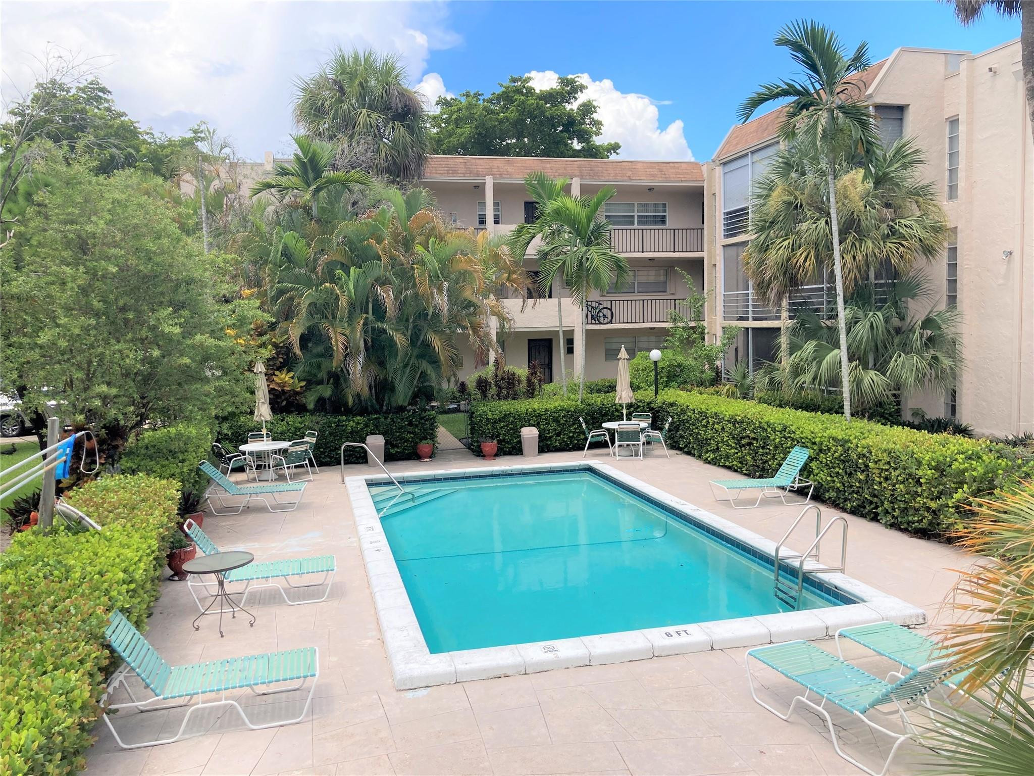 469 North Pine Island Road, Unit 308B Plantation, FL 33324 - Photo 2 of 16 a view of a swimming pool with potted plants and a large tree