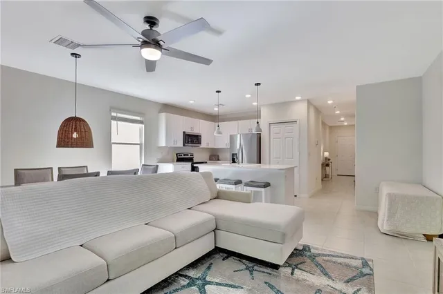 a kitchen with stainless steel appliances a refrigerator a stove a sink a microwave a dining table and chairs with wooden floor