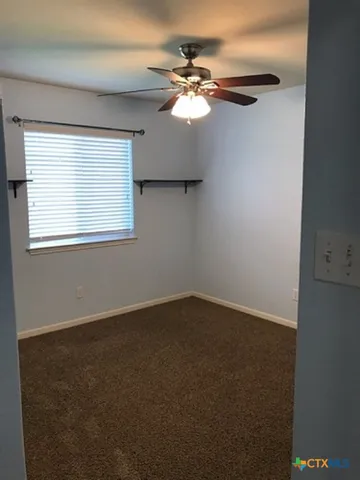 an empty room with windows and chandelier fan