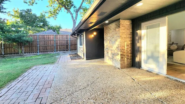 a view of a backyard with wooden fence and large trees