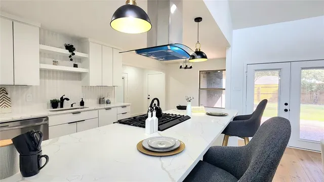 a kitchen with stainless steel appliances a table chairs and a wooden floor