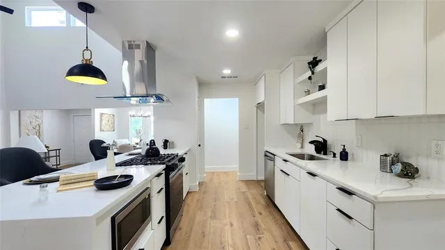 a kitchen with stainless steel appliances a stove a sink a refrigerator and chairs