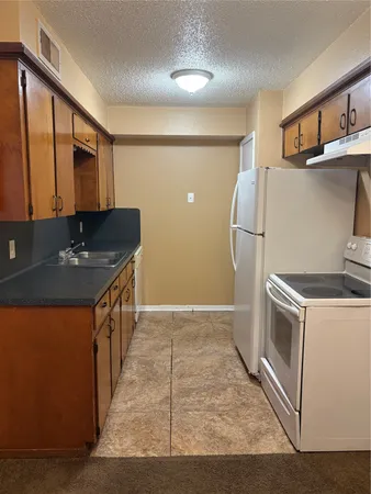 a kitchen with stainless steel appliances granite countertop a refrigerator a stove and a sink