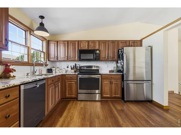 a kitchen with granite countertop wooden floors stainless steel appliances and sink