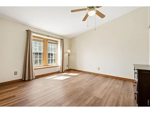 a view of an empty room with a window and wooden floor