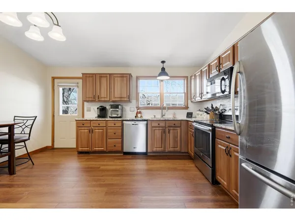 a kitchen with granite countertop a refrigerator cabinets and wooden floor