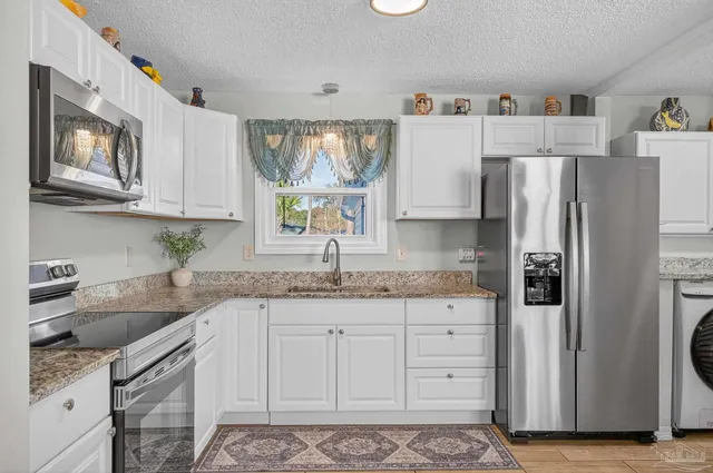 a kitchen with granite countertop white cabinets stainless steel appliances and a sink