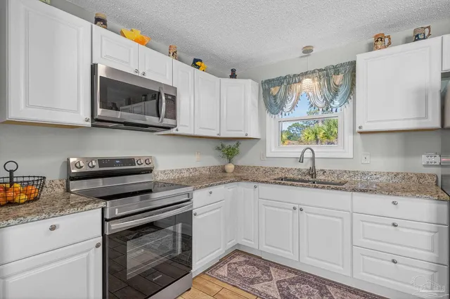 a kitchen with a sink and a stove with wooden floor