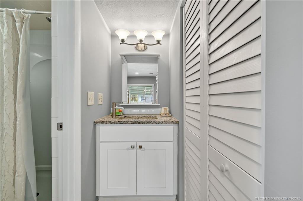 3260 Southeast Aster Lane, Unit I241 Stuart, FL 34994 - Photo 26 of 48 a bathroom with a granite countertop sink and a mirror