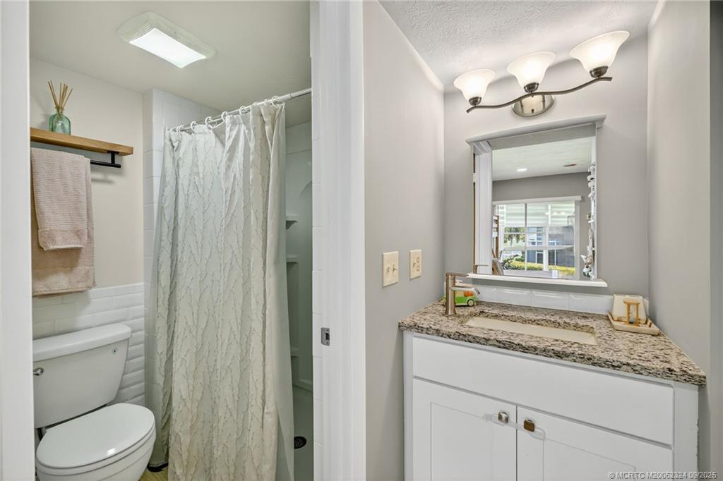 3260 Southeast Aster Lane, Unit I241 Stuart, FL 34994 - Photo 27 of 48 a bathroom with a granite countertop sink toilet and shower