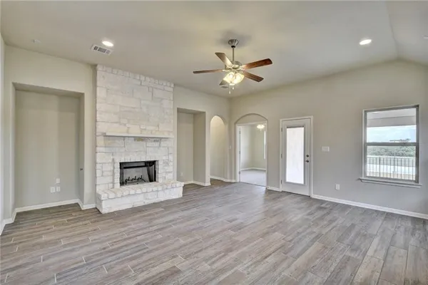 an empty room with wooden floor fireplace and windows