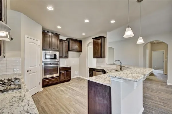 a kitchen with kitchen island granite countertop a sink cabinets and stainless steel appliances