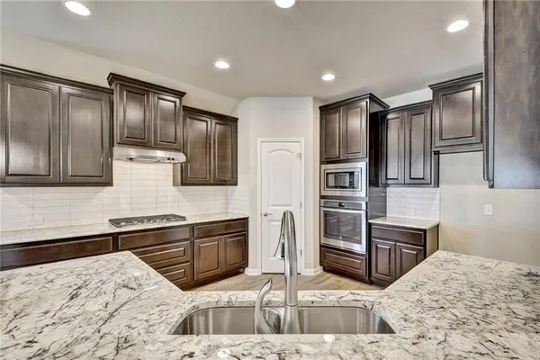 a kitchen with stainless steel appliances kitchen island granite countertop a refrigerator stove and sink