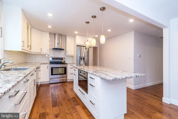a kitchen with granite countertop a sink cabinets and wooden floor