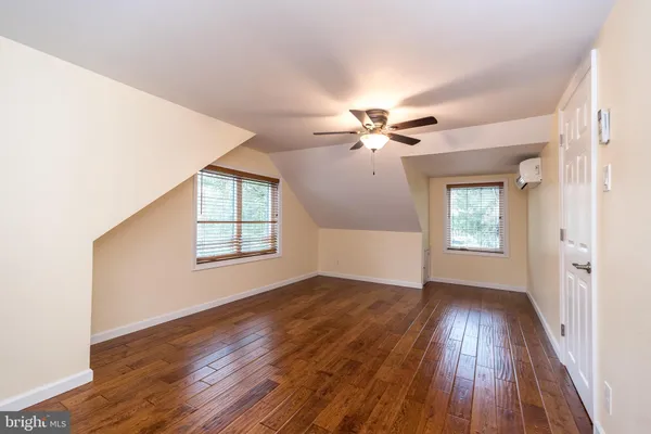 an empty room with wooden floor chandelier fan and windows
